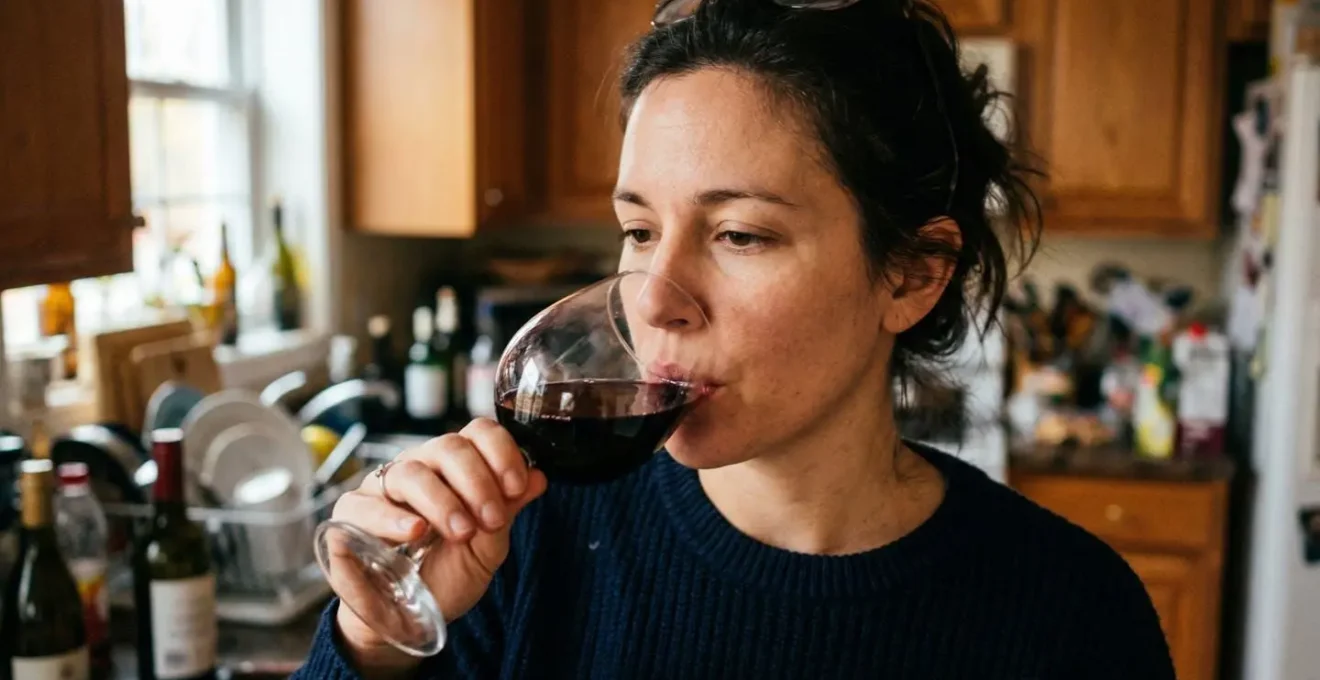 Un homme déguste une gorgée de vin rouge, le verre légèrement incliné vers ses lèvres